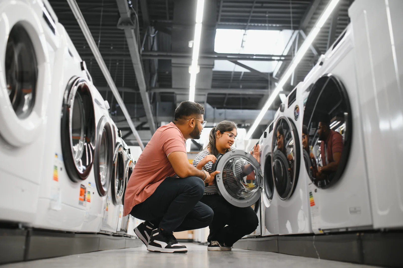 Couple comparing appliances of different brands in a showroom