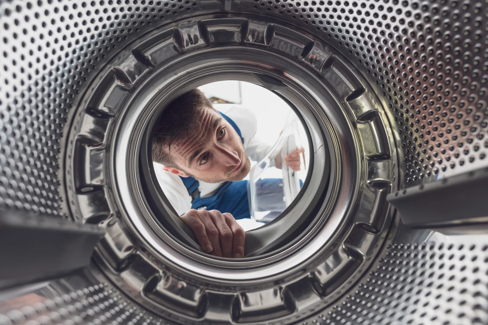 Technician inspecting a washing machine drum and seal from the inside